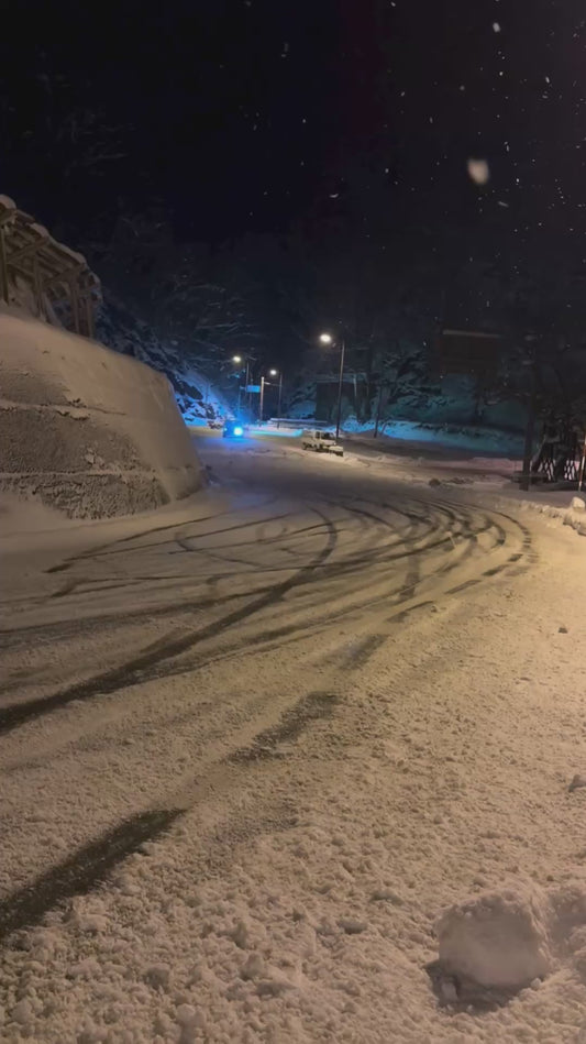 Trucks Drift Round Bend on Snowy Road